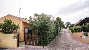 Une rue pavée, bordée d’une clôture en bois et d’un bâtiment jaune d’un côté.