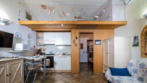 Une cuisine compacte avec un coin repas, un lit recouvert d’une couvre-lit à motifs et un plafond agrémenté d’éléments décoratifs.