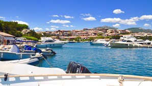 A marina with boats docked, a town in the background, and clear skies. - Monte Majore 16 B in Porto Rotondo (Olbia)