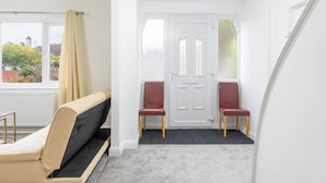 Une pièce comprenant un canapé, deux fauteuils, une porte et une fenêtre avec des rideaux.