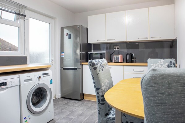 Une cuisine compacte équipée d’un lave-linge, d’un réfrigérateur, d’un four à micro-ondes et d’un grille-pain.
