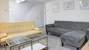 Un salon avec un canapé beige, un canapé gris et une table basse en verre.