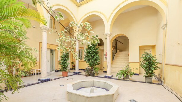 A courtyard with a central fountain, surrounded by columns and potted plants. - Villa Claudia in Sevilla (Seville)