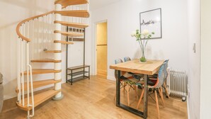 A modern interior with a spiral staircase, a dining area with a wooden table and chairs, and a framed picture on the wall. - Villa Claudia in Sevilla (Seville)