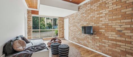 Una camera moderna con parete in mattoni, soffitto in legno e una grande finestra.