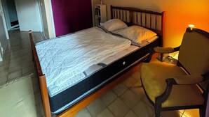 A bedroom with a bed, a chair, a bedside table, and a lamp.