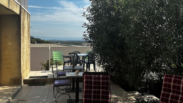 An outdoor patio with wicker chairs and a table, overlooking a scenic view.