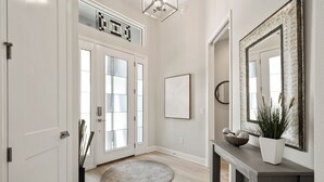 Un couloir avec un tapis rond, une console sur laquelle est posée une plante en pot et un grand miroir au mur.