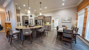 A spacious kitchen with a central island, wooden flooring, and pendant lighting. - Veteran’s Family Retreat, Spacious & Peaceful Stay Near AFB (Sherwood)