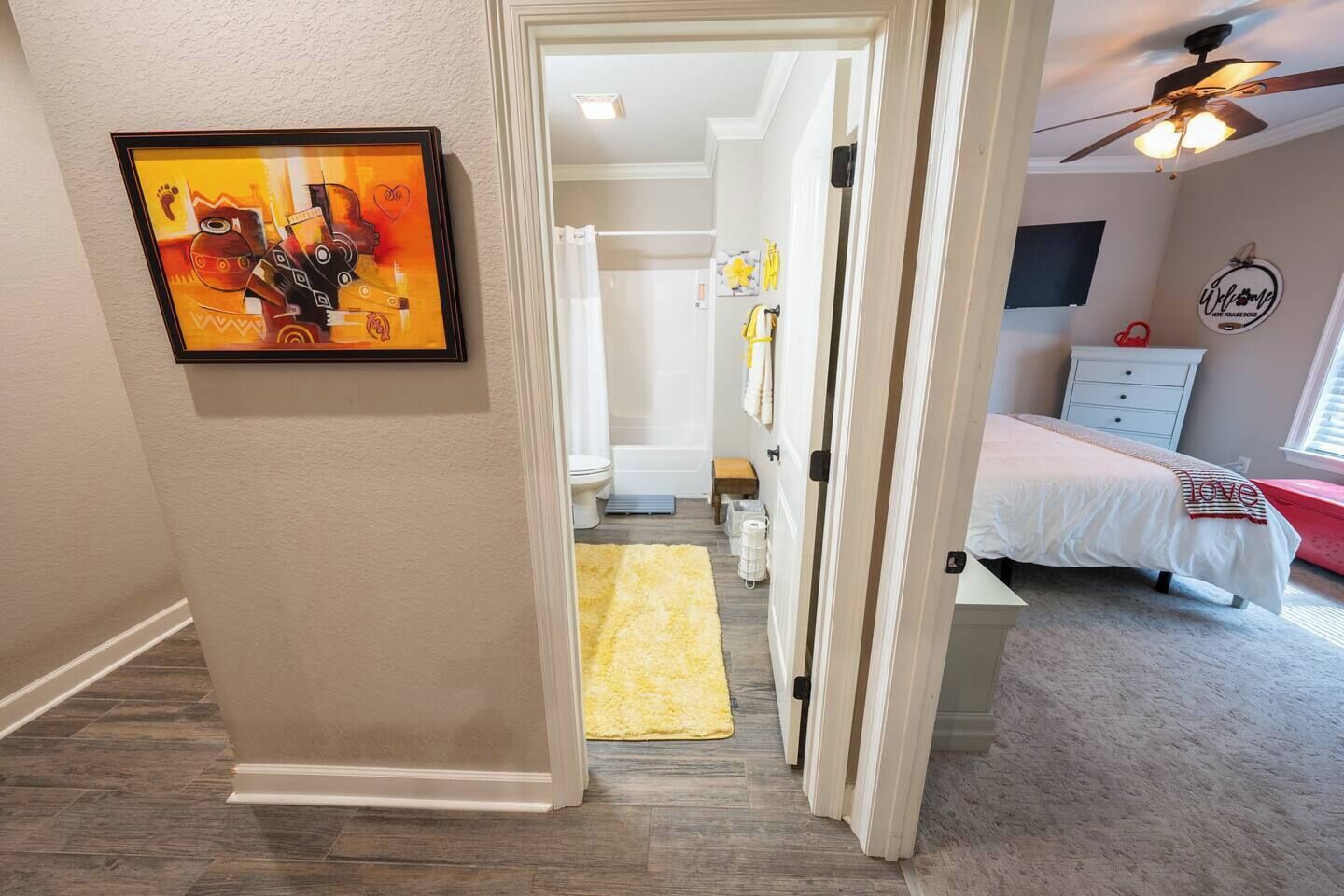 Une chambre à coucher avec un lit, un ventilateur de plafond et un tableau encadré accroché au mur.