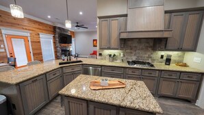 A modern kitchen with granite countertops, wooden cabinets, a central island, and a built-in stove. - Veteran’s Family Retreat, Spacious & Peaceful Stay Near AFB (Sherwood)