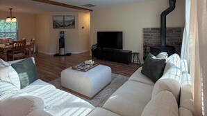 A living room with a sofa, a coffee table, a TV, and a fireplace. - Maple Cottage at Miller Lake: Your Serene Nature Escape (Miller Lake)