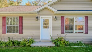 A single-story house with a front door, two windows with shutters, and a small porch area. - Maple Cottage at Miller Lake: Your Serene Nature Escape (Miller Lake)