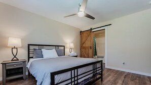 A bedroom with a bed, two bedside tables with lamps, a ceiling fan, and a wooden wardrobe. - Maple Cottage at Miller Lake: Your Serene Nature Escape (Miller Lake)