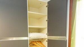 A walk-in closet with grey doors, wooden hangers, and a radiator.