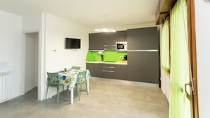 A modern kitchen with grey cabinets, a green countertop, and a dining area with a table and chairs.