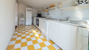 Une cuisine avec un carrelage à motifs, des placards blancs, un évier et une cuisinière.