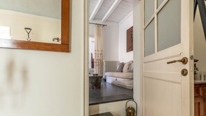 A hallway with a white door, a mirror, a radiator, a white sofa, and a small table with a lantern. - Ale Cozy House by Wonderful Italy (Palermo)