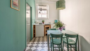 A compact kitchen with a checkered floor, a dining area with two chairs, and a hanging pendant light. - Ale Cozy House by Wonderful Italy (Palermo)