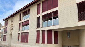 Ein mehrstöckiges Gebäude mit beiger Fassade, roten Fensterläden und einer Garagentür.