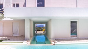 A modern house with a swimming pool, a covered patio, and a view of a mountain.