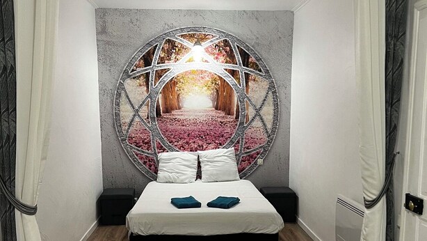 Een slaapkamer met een ronde wanddecoratie, een bed met witte lakens en een houten vloer.