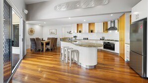 A modern kitchen with a central island, wooden flooring, and stainless steel appliances.