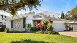 A modern two-story house with a stone facade, a garage, and a well-maintained lawn.