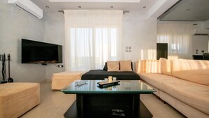 A modern living room with a flat-screen TV, a glass coffee table, a sofa, and a loveseat. - Calm and Joy Summer House  (8527+7F4 Afantou, Greece)