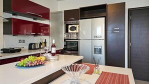 A modern kitchen with red cabinetry, a stainless steel refrigerator, and a microwave. - Calm and Joy Summer House  (8527+7F4 Afantou, Greece)