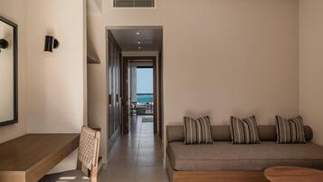 Habitación de hotel moderna con sofá, una mesa de madera, una silla y vista al océano.