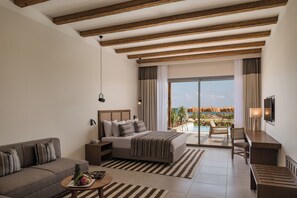 Una habitación de hotel moderna con una cama grande, un sofá, un escritorio y vistas a una piscina y una playa.