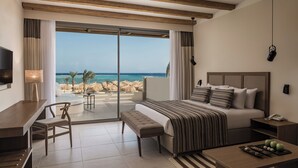 A modern hotel room with a large bed, a desk, and a view of the beach. - JAZ Elite Riviera (Marsa Alam)