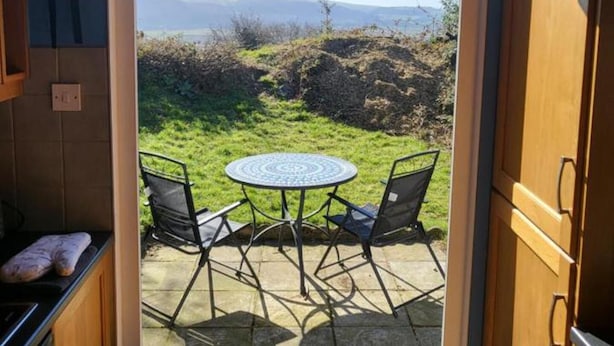 Una cocina con vistas a un área verde y montañas a través de un ventanal.