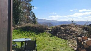 Un patio con mesa y sillas, una valla de madera y vistas a montañas distantes.