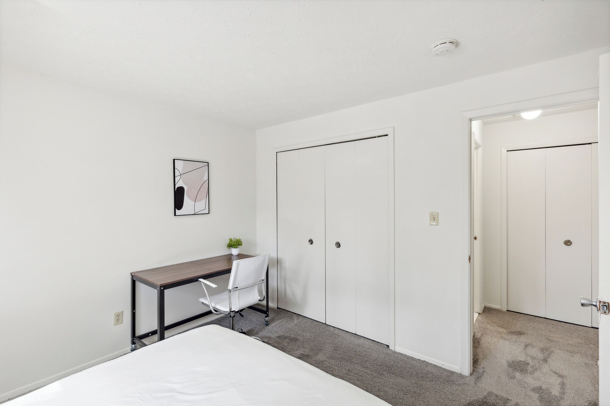 Une chambre à coucher avec un lit, un bureau, une chaise et une armoire.