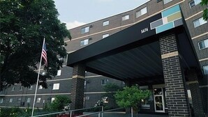 A multi-story building with a brick facade, a black awning over the entrance, and an American flag.
