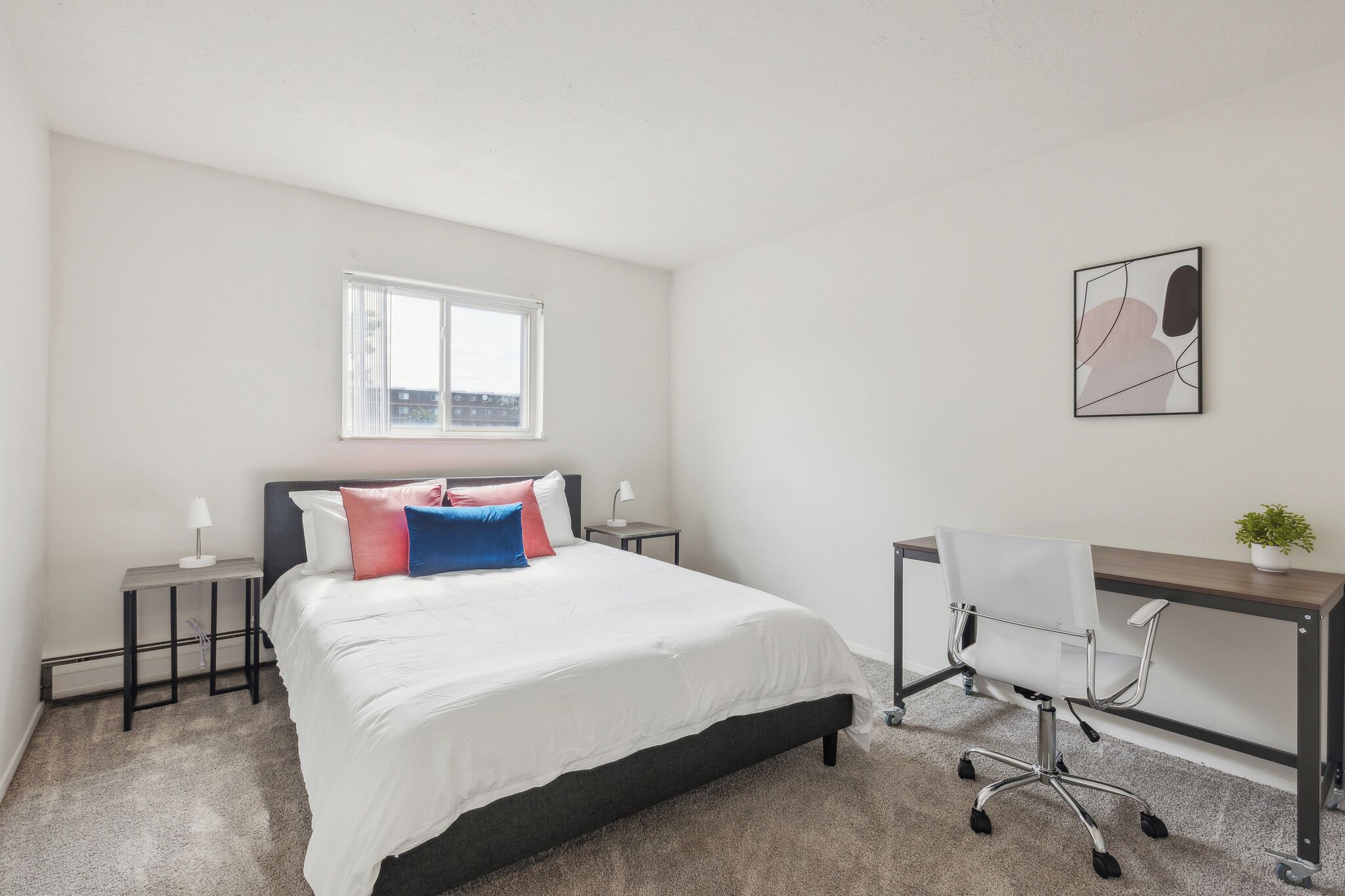 Une chambre à coucher comprenant un lit, des tables de chevet, un bureau et une chaise.