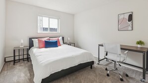 Une chambre à coucher comprenant un lit, des tables de chevet, un bureau et une chaise.