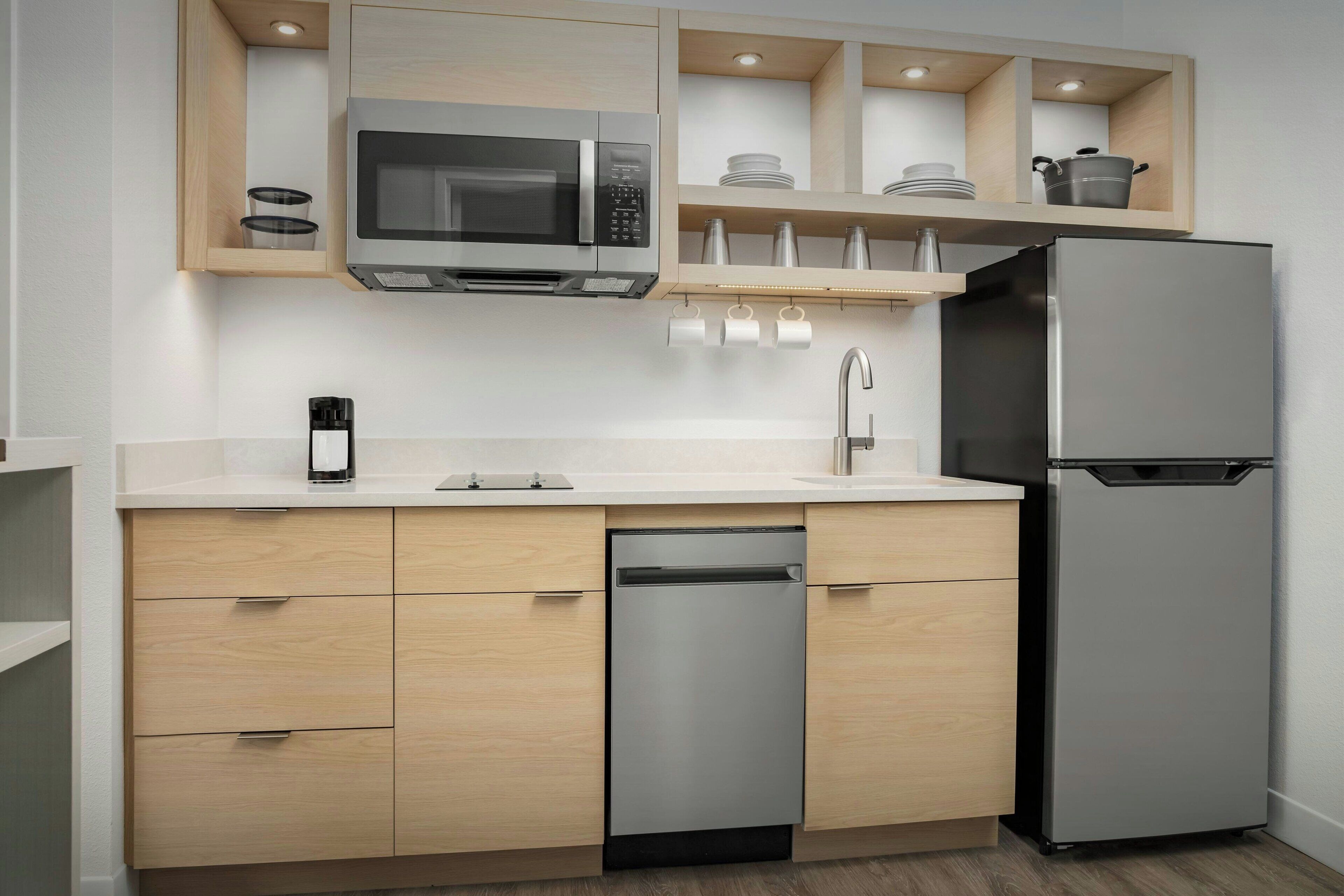 A modern kitchen with a built-in microwave, stainless steel refrigerator, and a dishwasher.