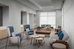 A modern lounge area with seating arrangements, including sofas and chairs, and small round tables.