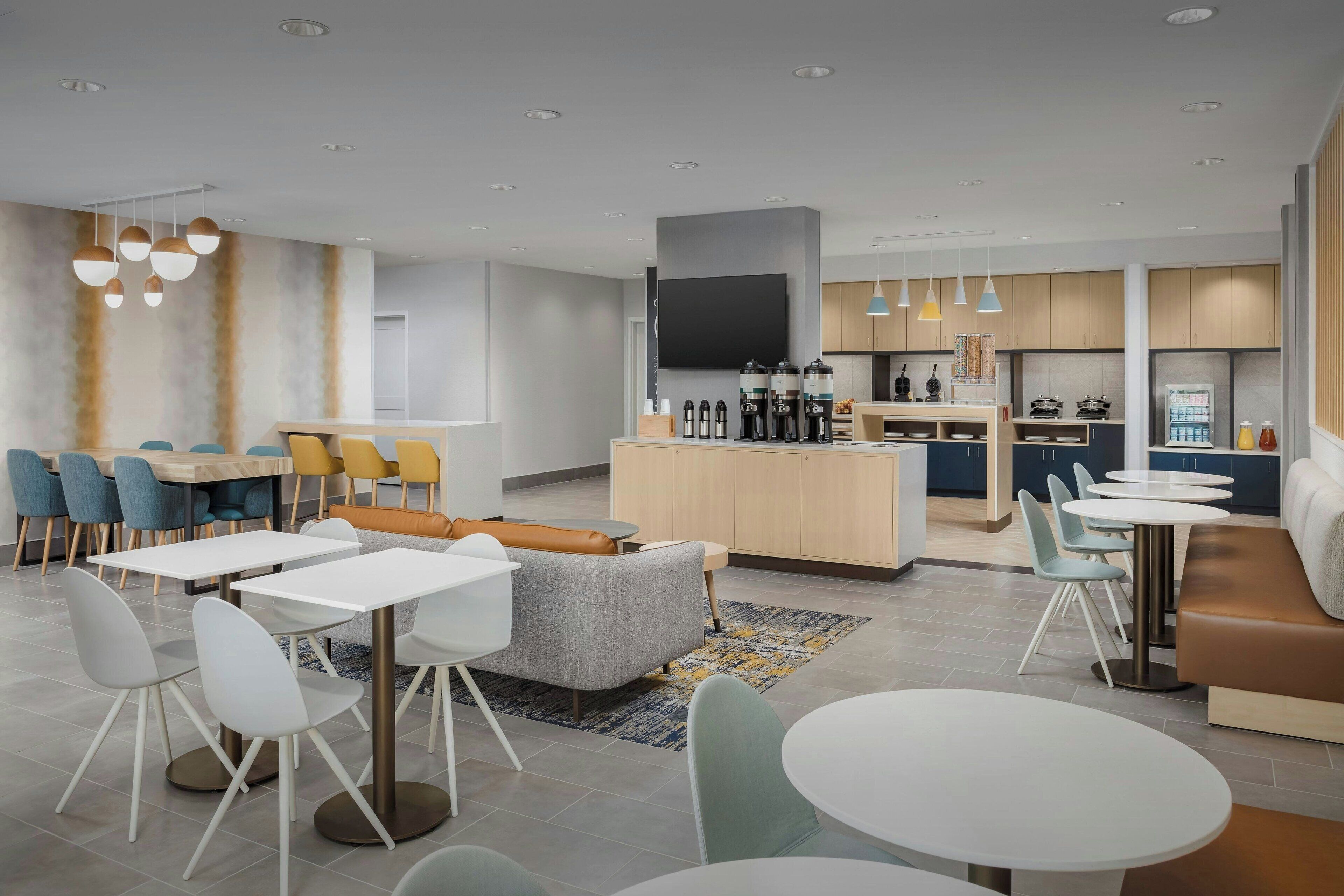 Eine moderne Hotelhalle mit Essbereich, Küche und Sitzgelegenheiten.
