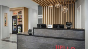 Un'area di reception hotel con un cartello che dice 'HELLO', un minibar e una sezione denominata 'PINCH'.