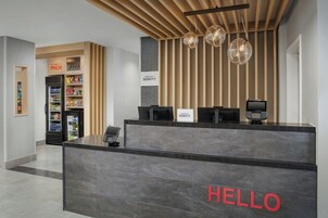 A hotel reception area with a 'HELLO' sign, a minibar, and a 'PINCH' section.