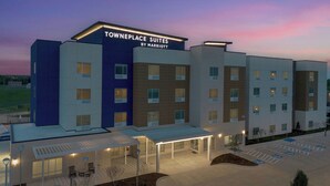 Un hotel a più piani con un cartello che indica "Towneplace Suites by Marriott" e una zona esterna coperta con tavoli e sedie.