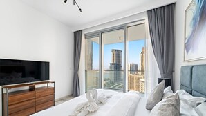 Une chambre d’hôtel avec un grand lit, une télévision, une commode en bois et un balcon offrant une vue sur la ville.