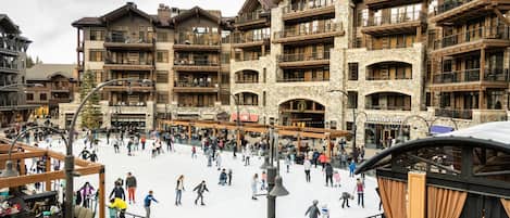 Uma estação de esqui com edifícios de vários andares, uma pista de patinação no gelo e áreas de estar ao ar livre.