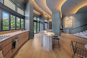 Una cocina moderna con una isla central, ventanas amplias y una escalera que lleva a un nivel superior.