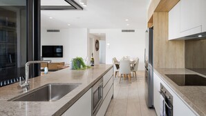 Eine moderne Küche mit einer großen Kochinsel, integrierten Geräten und einem Essbereich mit Tisch und Stühlen.