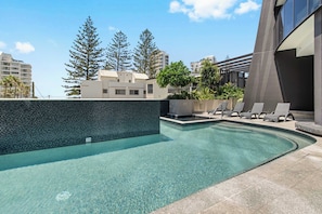 Ein Schwimmbecken mit klarem Wasser, umgeben von Liegestühlen und einer gefliesten Terrasse.